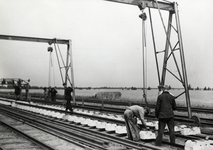 168928 Afbeelding van het monteren van spoorstaven op betonnen dwarsliggers ten behoeve van de spoorlijn tussen Helmond ...